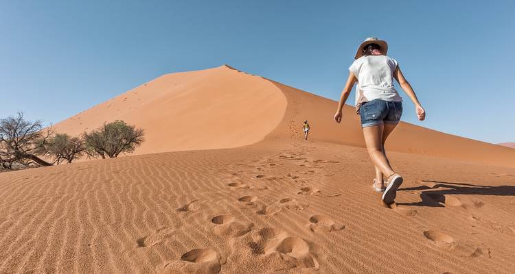 Des gens qui font de la randonnée sur des dunes de sable.