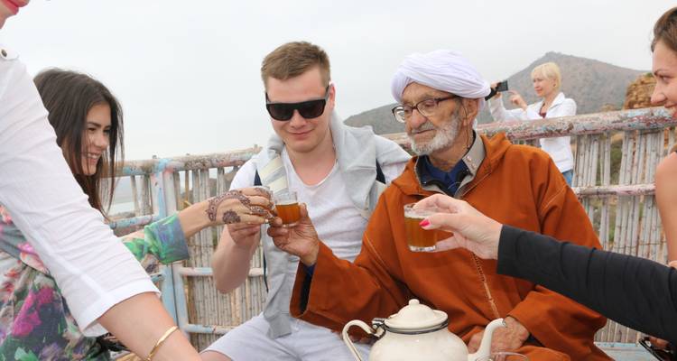 Groupe de personnes savourant le thé en plein air dans un cadre décontracté.