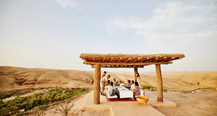 Gruppe von Menschen, die im Freien mit Blick auf die Wüste speisen.