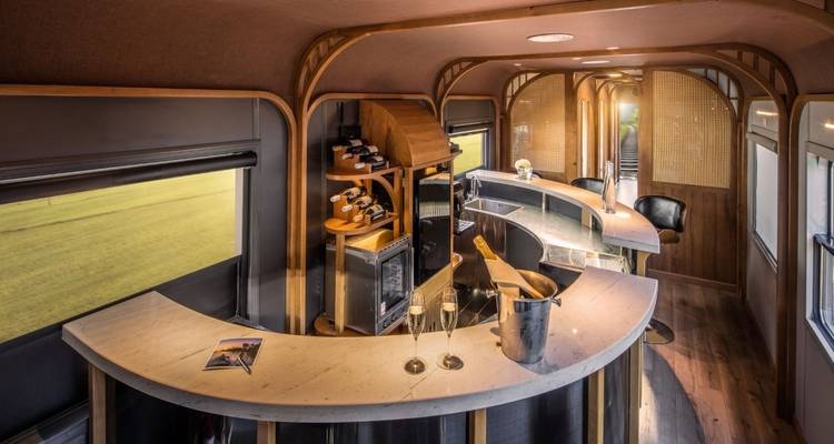 Interieur van een luxe treinbar met een gebogen toonbank en stoelen.