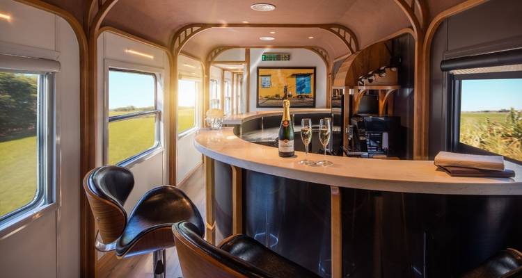 Luxe treinbar interieur met champagne en een helder schilderachtig uitzicht buiten.