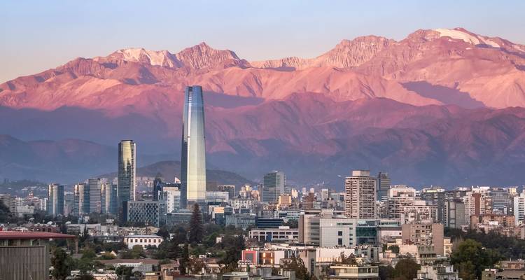Le skyline moderne de Santiago avec des gratte-ciel imposants encadrés par les montagnes des Andes aux teintes roses au crépuscule.