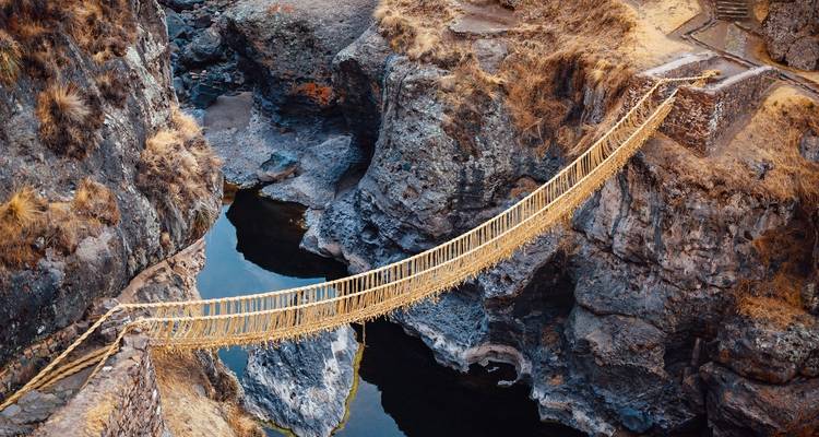 Luchtfoto van een traditionele touwbrug over een diepe kloof.