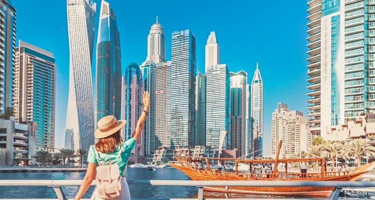 Une femme saluant de la main le panorama de Dubai Marina avec ses gratte-ciel.