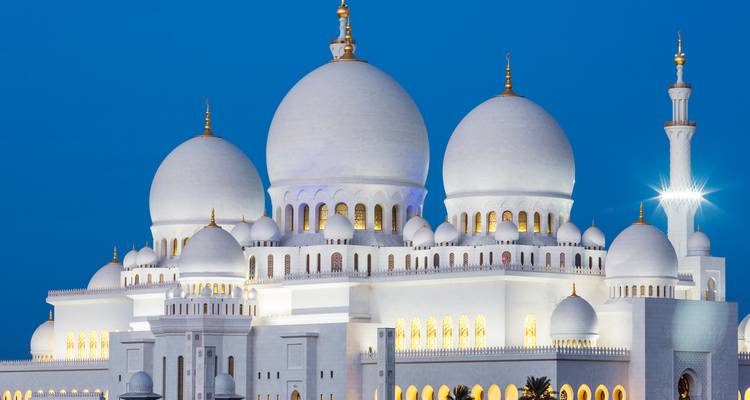 Grande Mosquée Sheikh Zayed au coucher du soleil sous un ciel bleu dégagé.