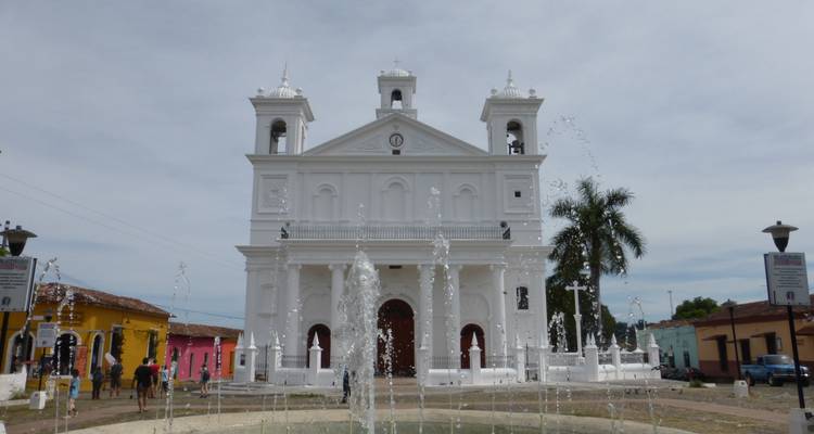 Witte kerk met waterfontein ervoor.