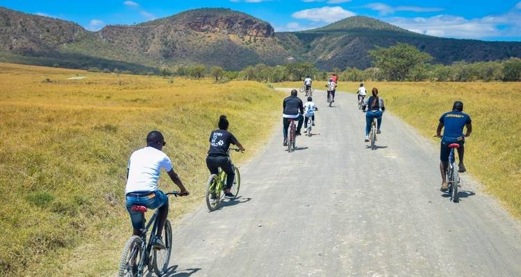 Groep mensen die fietsen op een onverharde weg door een savannelandschap.