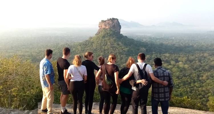 Groupe de personnes sur une montagne avec une formation rocheuse distinctive en arrière-plan.