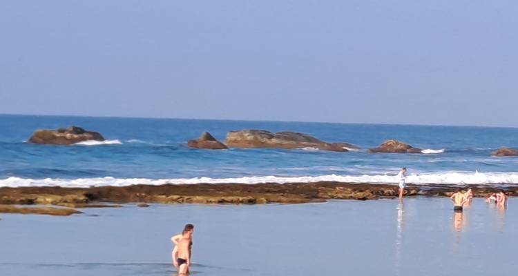 People swimming and sunbathing at the beach.