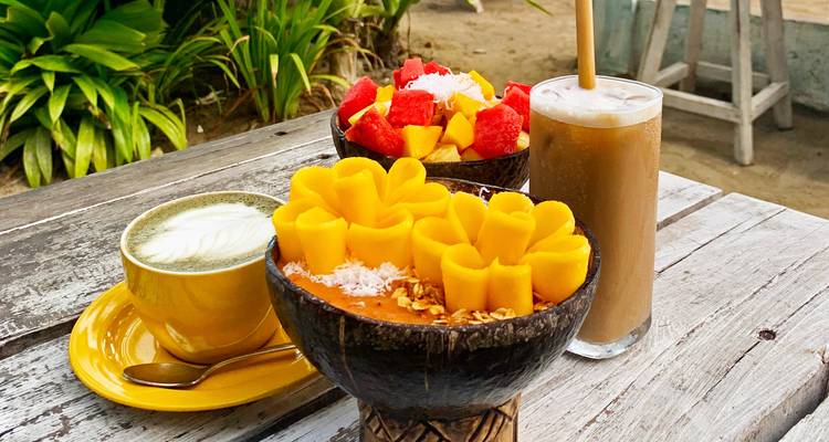 Close-up van kleurrijke kommen met eten en drankjes op een houten tafel.