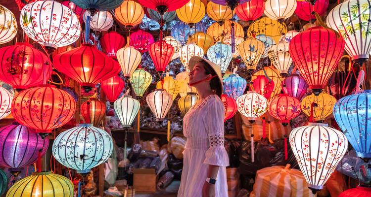 Kleurrijke lantaarns die aan het plafond hangen met een vrouw die ernaar kijkt.