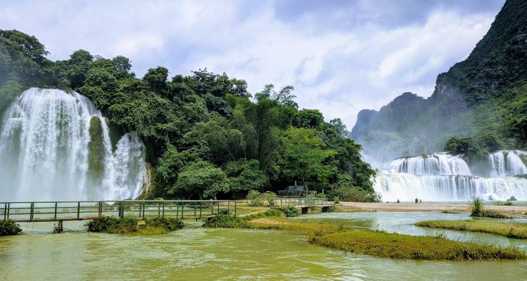 Des cascades se jetant dans une rivière dans un paysage luxuriant.