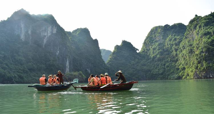 Des touristes en bateau sur une rivière entourée de falaises calcaires.