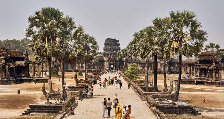 Menschen gehen auf Tempelstrukturen zwischen Palmen zu mit klarer Sicht.