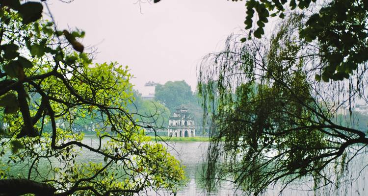 Tempel inmitten eines Sees, umgeben von üppigem Grün.