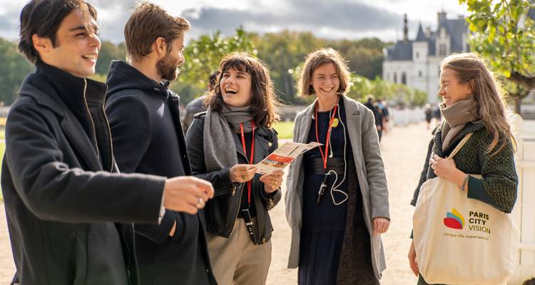 A group of tourists enjoying a conversation in front of a castle.
