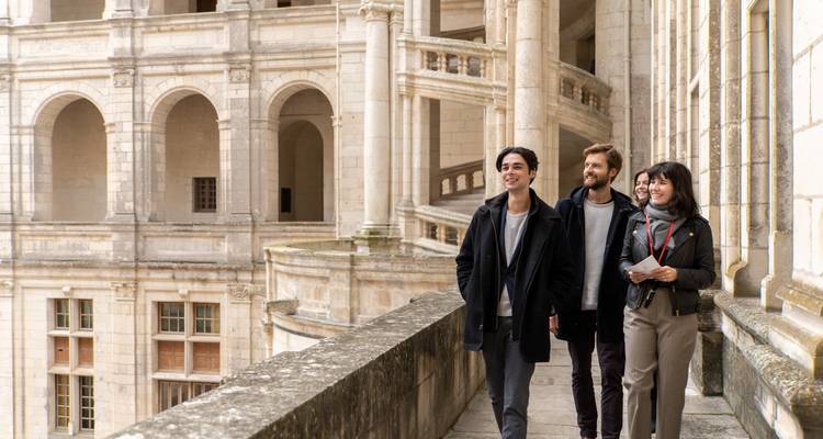 Group of tourists walking along a balustrade in a historical building.