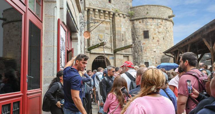 Las multitudes hacen cola en la puerta de piedra del pueblo de Mont Saint-Michel bajo cielos azules