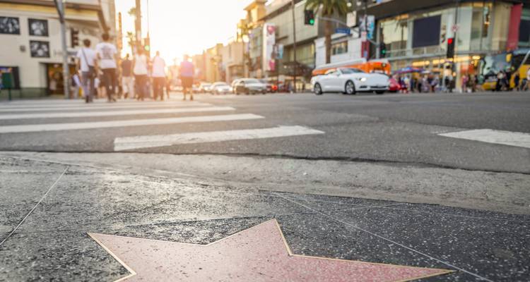 Vue de rue avec un focus sur une étoile sur le trottoir et des gens qui traversent