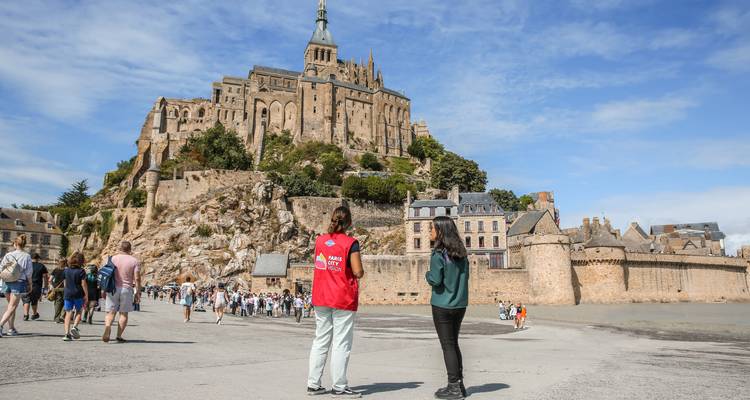 Toeristen die Mont Saint-Michel verkennen onder een heldere hemel