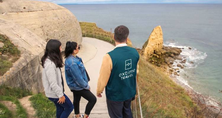 Los viajeros observan un búnker costero de la Segunda Guerra Mundial y acantilados marinos en la costa de Normandía