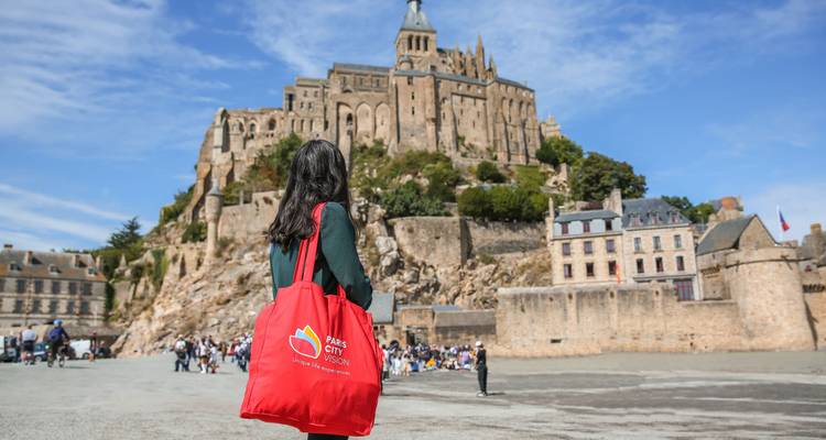 Touriste avec un sac rouge regardant le Mont Saint-Michel