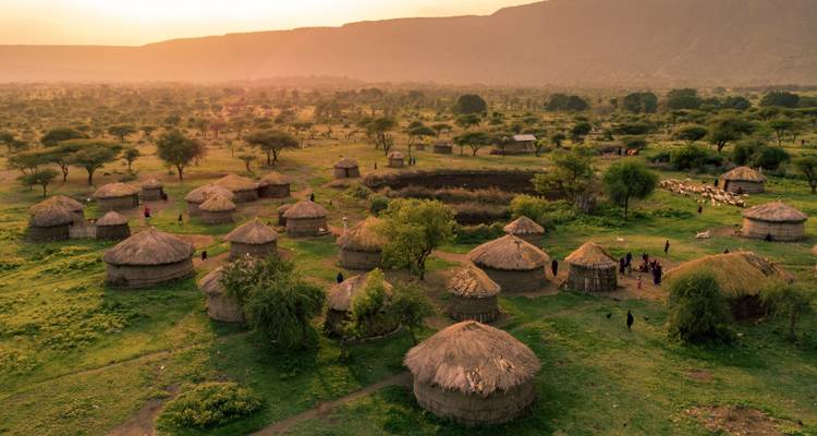 Traditionelle Hütten in einer ländlichen Landschaft bei Sonnenuntergang.