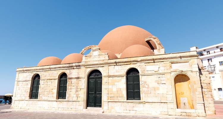 Die rosa gekuppelte Yiali Tzami Moschee steht einsam an Chanias alter Hafenfront unter einem klaren blauen Himmel.