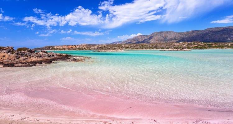 Prachtig strand met roze zand en kristalhelder water onder een heldere hemel.