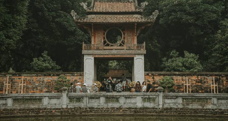 Puerta histórica con personas y árboles de fondo.