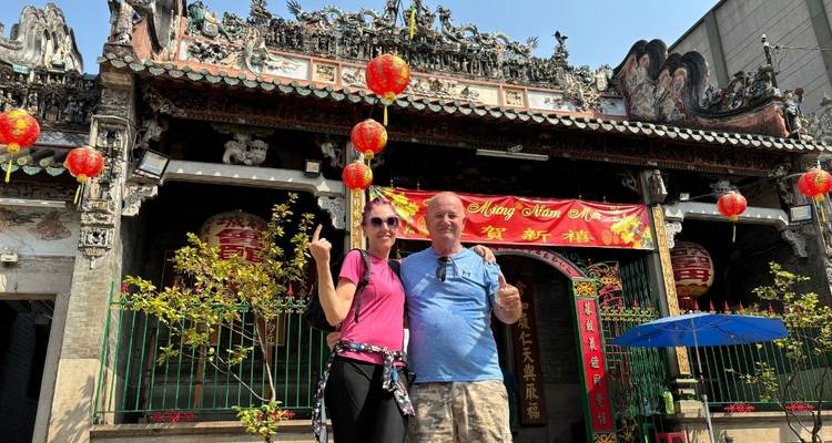 Personen, die vor einem traditionellen asiatischen Tempel mit roten Laternen posieren.