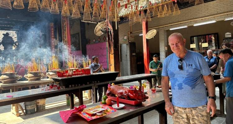 Einzelperson, die in einem Tempel in der Nähe eines Tisches mit religiösen Opfergaben steht.