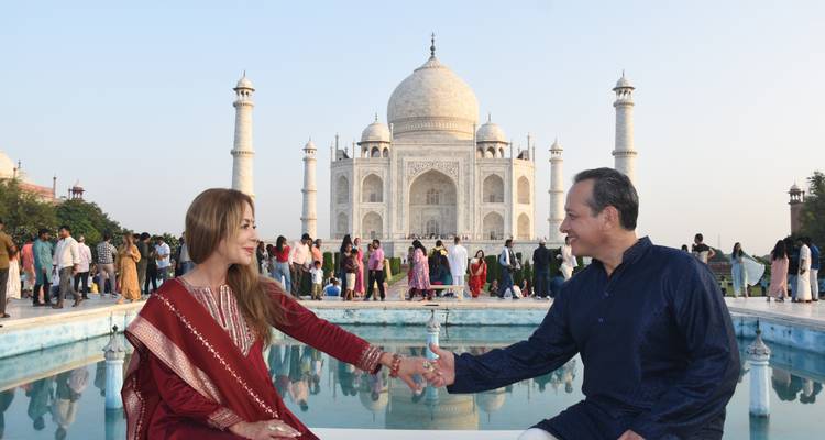 Una pareja tomada de la mano con el Taj Mahal de fondo.