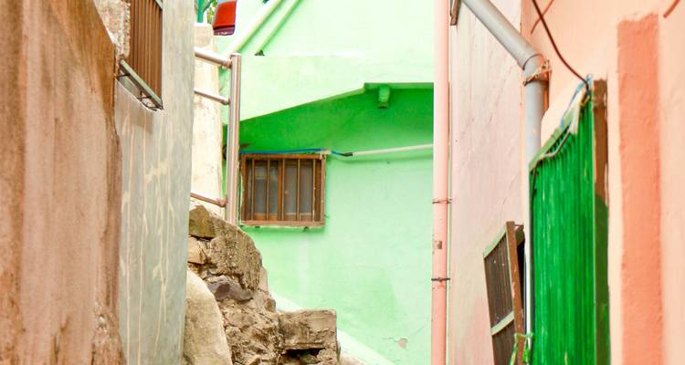 Un estrecho callejón pintado en colores pastel sube entre casas peculiares en la ladera.