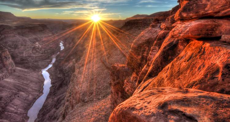 Zonsondergang boven een dramatisch canyonlandschap.