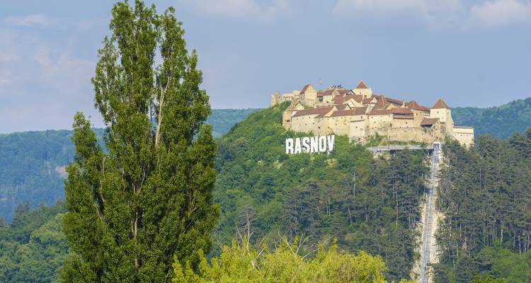 Blick auf die Festung Rasnov auf einem Hügel mit einem Schild.