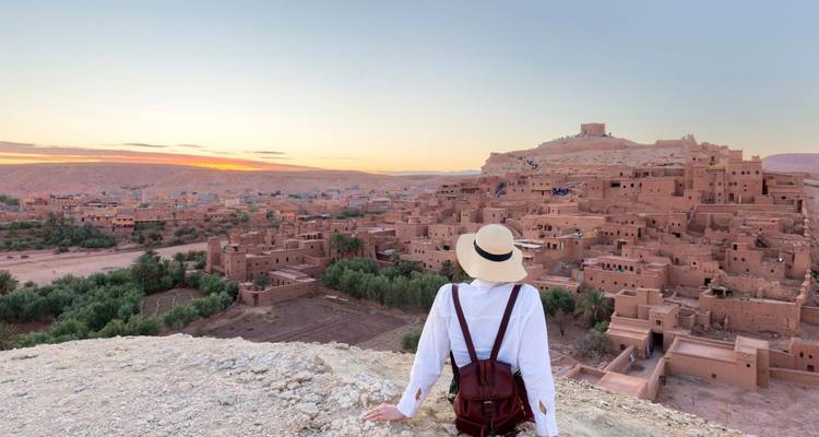 Eine Person, die bei Sonnenuntergang auf eine Wüstenstadt blickt.