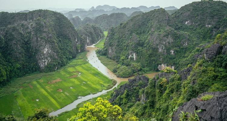 Valle verde con río serpenteante y colinas de piedra caliza.
