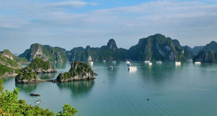 Bahía tranquila con embarcaciones e islotes de piedra caliza.