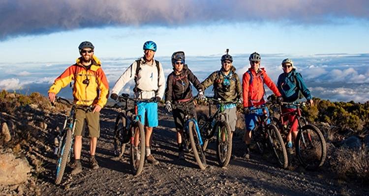 Groupe de cyclistes posant avec leurs vélos sur un sentier de montagne.