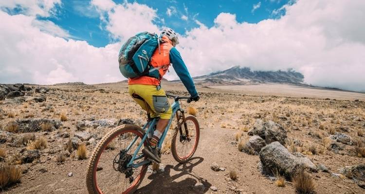 Cycliste roulant à vélo sur un paysage rocheux avec vue sur la montagne.