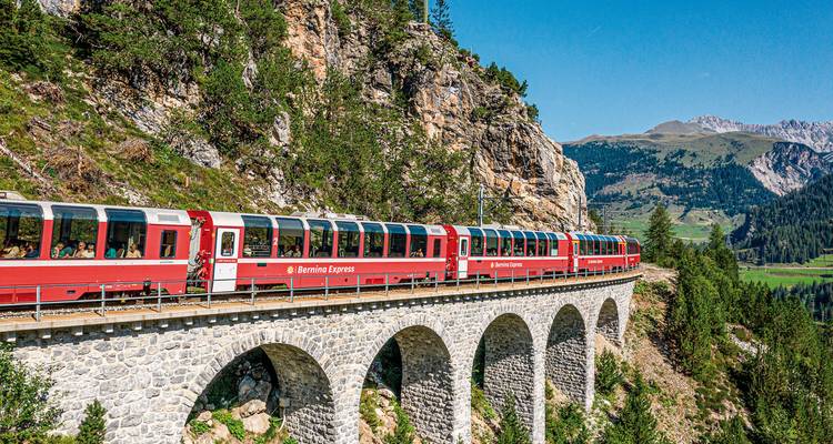 Bernina Express train on a viaduct in a mountainous area.