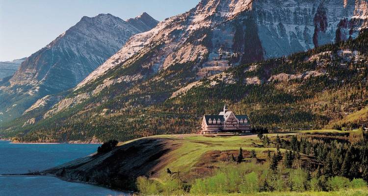 Historische lodge ligt op een grasachtig schiereiland naast een bergmeer omgeven door steile beboste toppen.