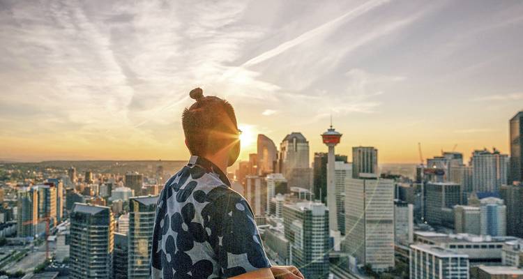 Una persona disfrutando de la vista del atardecer sobre el horizonte de una ciudad moderna.