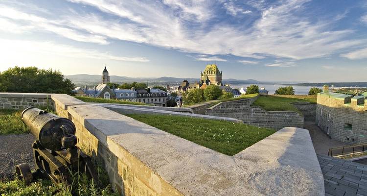 Murallas históricas de una fortaleza con vista a una ciudad y un río al fondo.