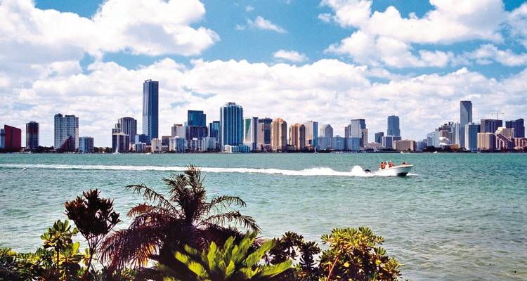 Skyline of a city with a speedboat on the water.