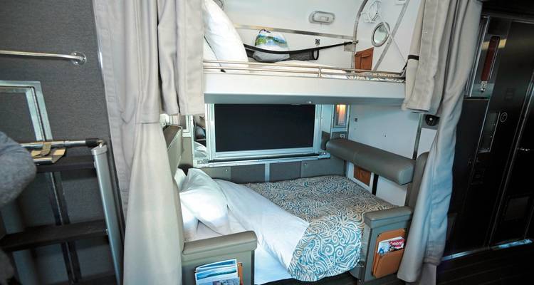 Cabine couchettes de train avec lits faits.