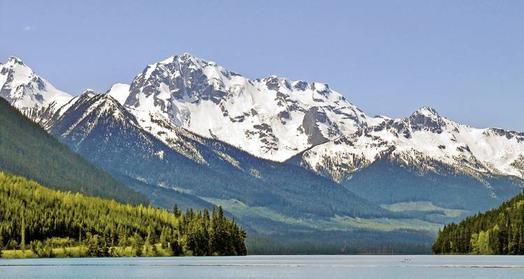 Besneeuwde bergen met meer op de voorgrond.