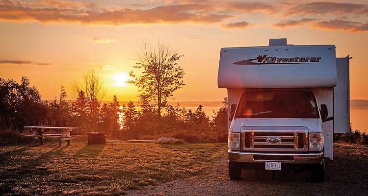 Camper geparkeerd bij zonsondergang met een schilderachtig uitzicht.