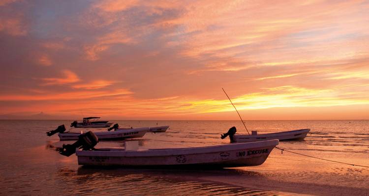 Magnifique coucher de soleil sur l'océan avec des bateaux silhouettés contre le ciel coloré.